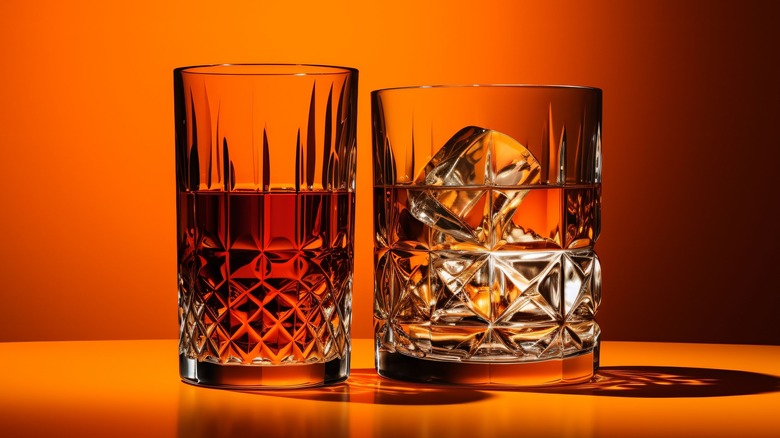 Two glasses of whiskey orange background