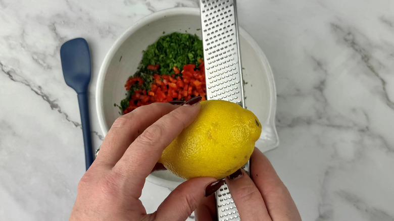 Hands zesting lemon into bowl