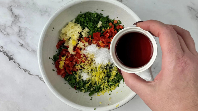 Small bowl of red wine vinegar over larger bowl of chimichurri