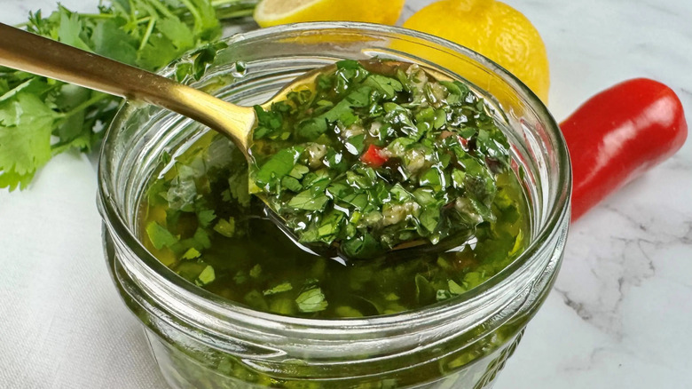 Spoon scooping chimichurri out of jar