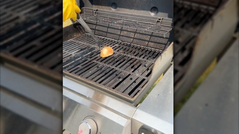Grill fork with onion half cleaning a hot grill.