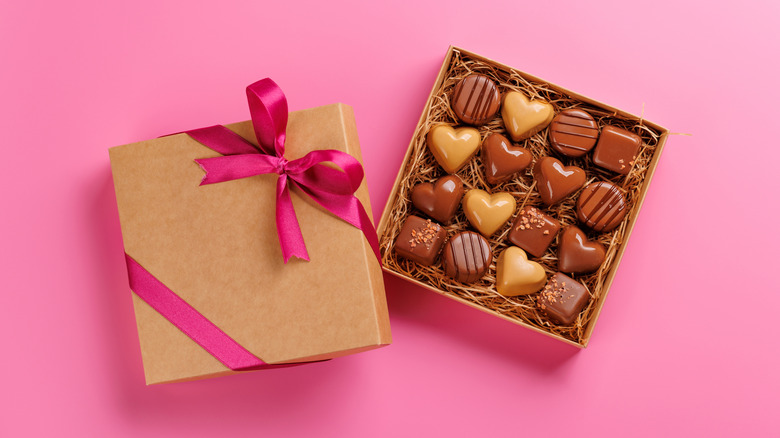 A gift box of chocolate hearts on a pink background