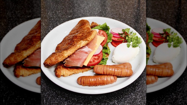 Smashed croissant sandwich with cheese, tomatoes and meats