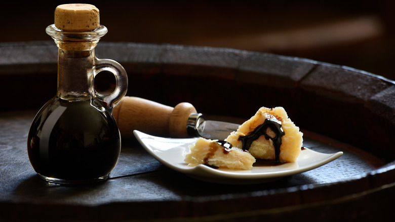 Traditional balsamic vinegar in a flask and drizzled over Parmigiano-Reggiano cheese 