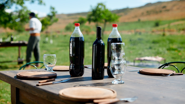 Two bottles of Coke and a red wine bottle on a table outdoors