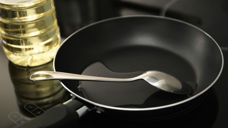 Spoon in frying pan with oil on stove