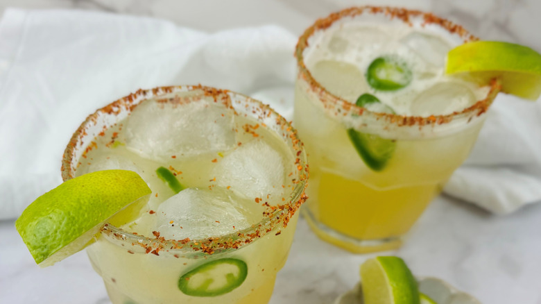 TWo margaritas with lime wedges and jalapeño slices