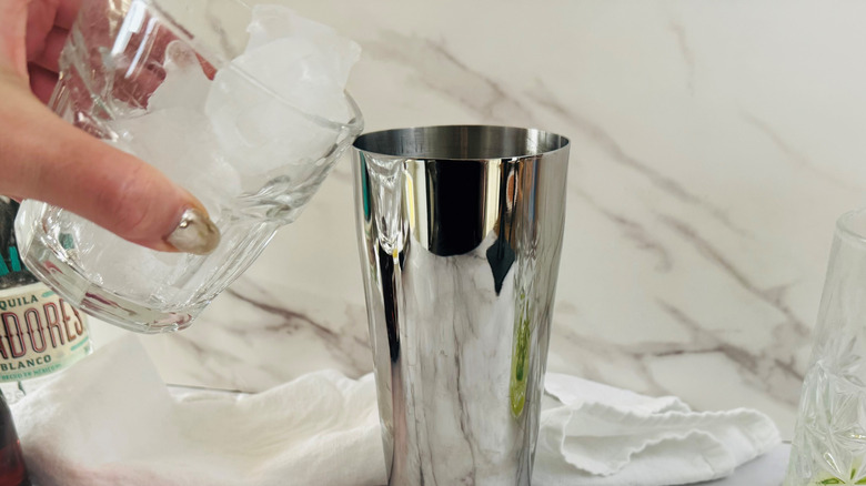 Cup of ice pouring into cocktail shaker