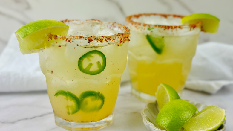 Two spicy margaritas next to bowl with lime wedges