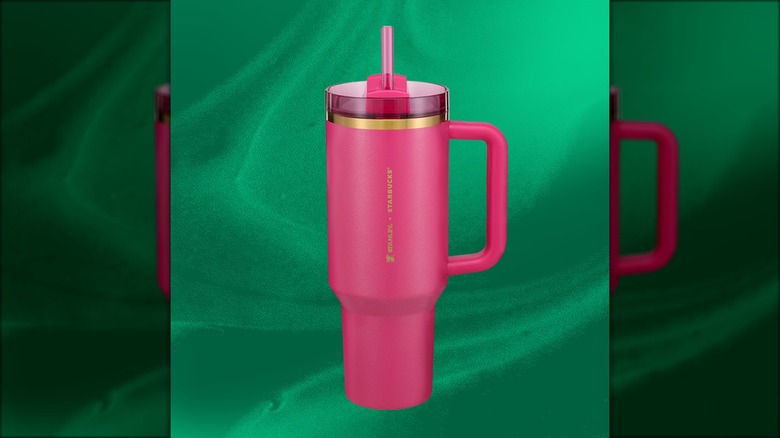 Starbucks' holiday Stanley cup is berry pink, with a gold rim and a translucent pink straw.