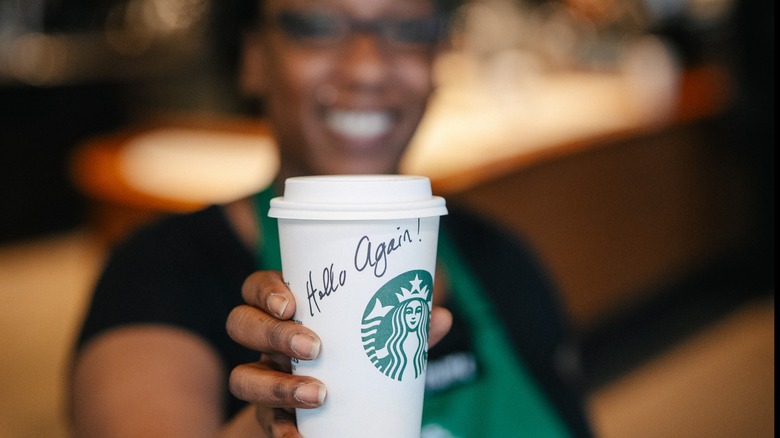 A Starbucks barista holds out a cup