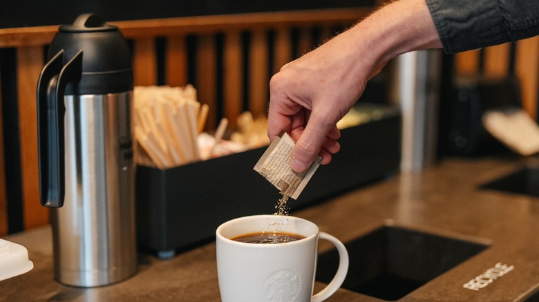 A Starbucks customer adds sugar at the condiment bar