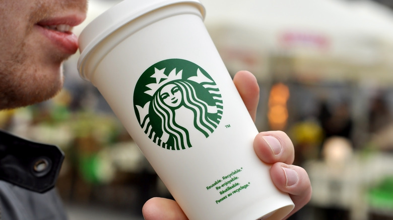 A man drinks a sip of his Starbucks beverage