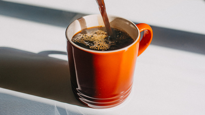 Pouring coffee into red mug