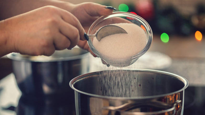 Adding granulated sugar to a pan from small glass bowl.