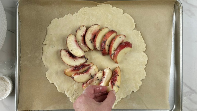 assembling sliced peaches on crust