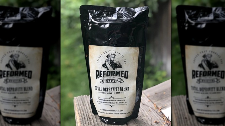 A packet of Reformed Roasters Total Depravity dark roast coffee pictured outside on a wooden surface