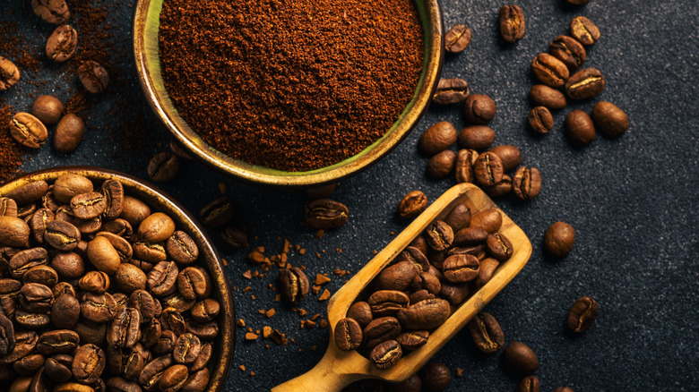 Roasted coffee beans, ground coffee and instant coffee in bowls at dark background