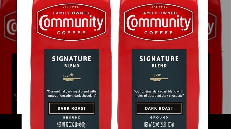 A close-up of two packets of Community Coffee Signature Blend Ground Coffee, Dark Roast