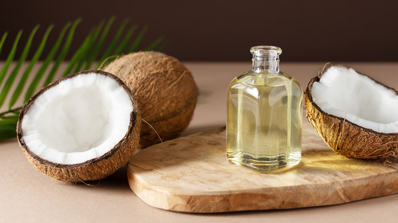 bottle of coconut oil sitting next to cracked open coconut