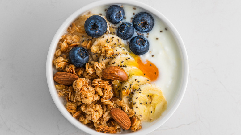 Chia seeds, granola, nuts, and fruit sprinkled on yogurt