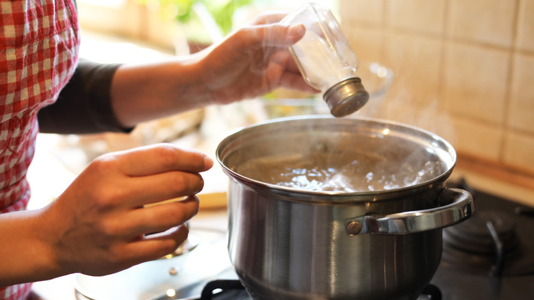 A person adding salt to water