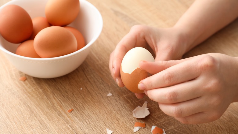 Person peeling hard boiled eggs