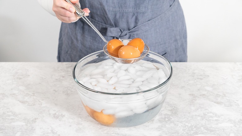 Person putting eggs in ice bath