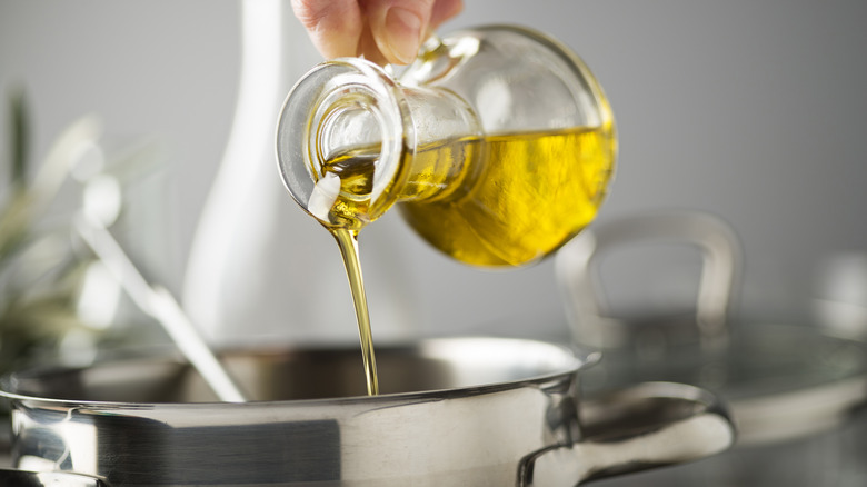 A person adding oil to a pan