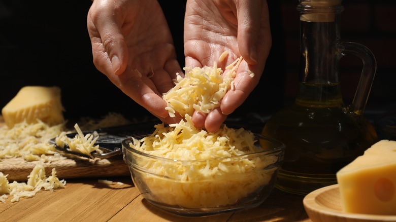 grated gouda cheese in a woman's hands