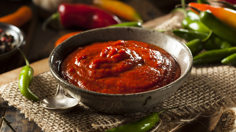 bowl of sriracha next to peppers