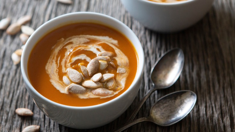 pumpkin soup with two spoons and pumpkin seeds