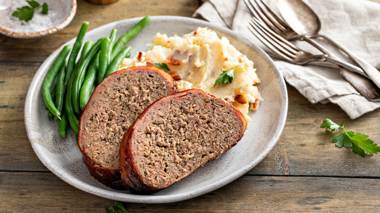 Meatloaf served with mashed potatoes and green beans.