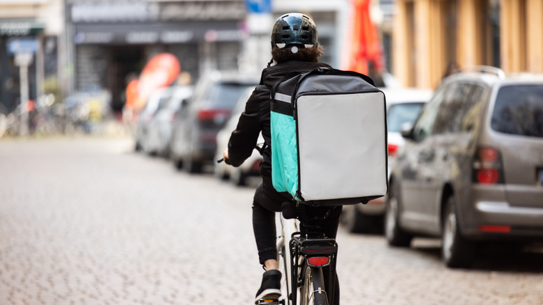 A bicyclist delivers food with a thermal backpack