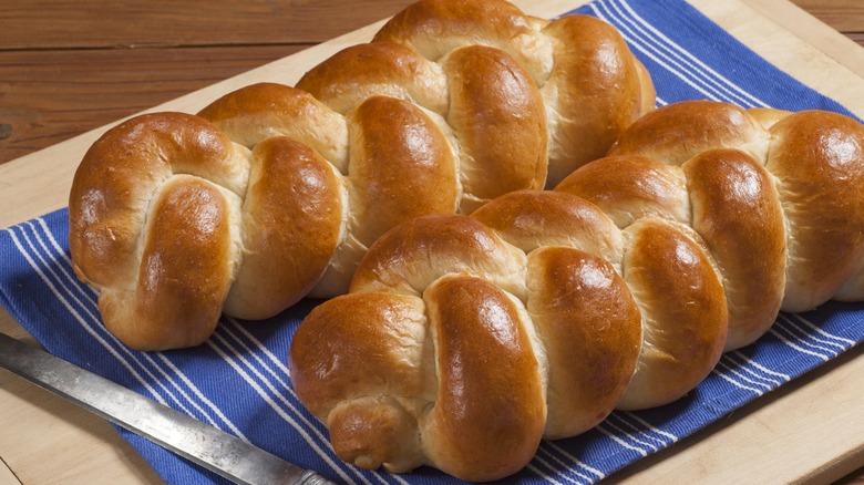 Two loaves of baked challah bread on blue towel