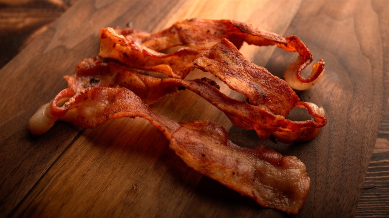 Three strips of crispy bacon on wood board