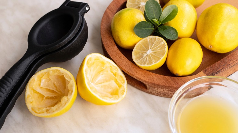 Hand juicer next to juiced lemons and lemon juice