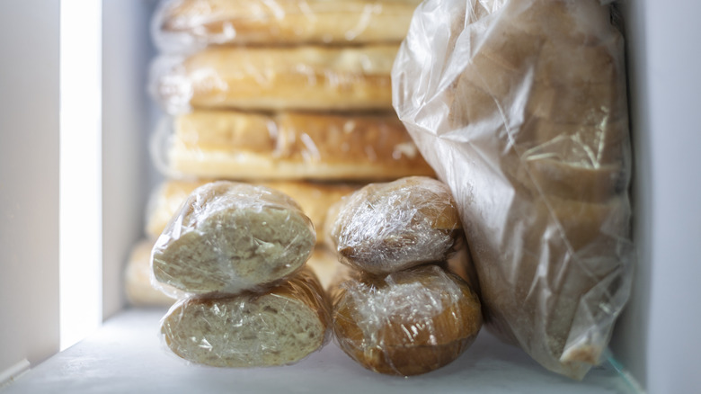 Plastic-wrapped loaves of bread in freezer.