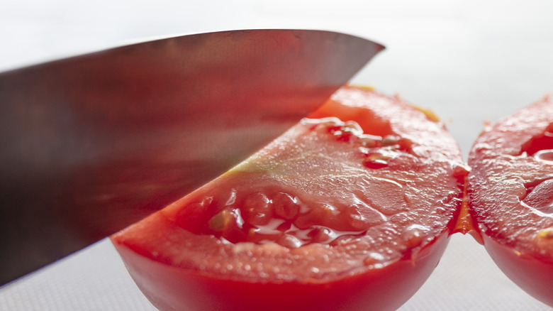 Knife slicing a tomato