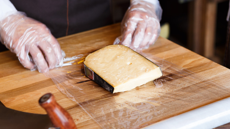 Person wrapping cheese in plastic