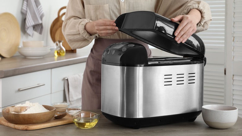 Person opening bread machine in kitchen