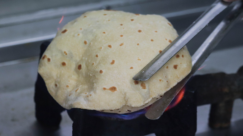 A soft roti getting fluffed up on an open flame