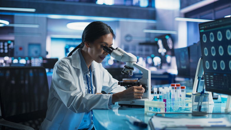 A scientist peers through a microscope in a lab