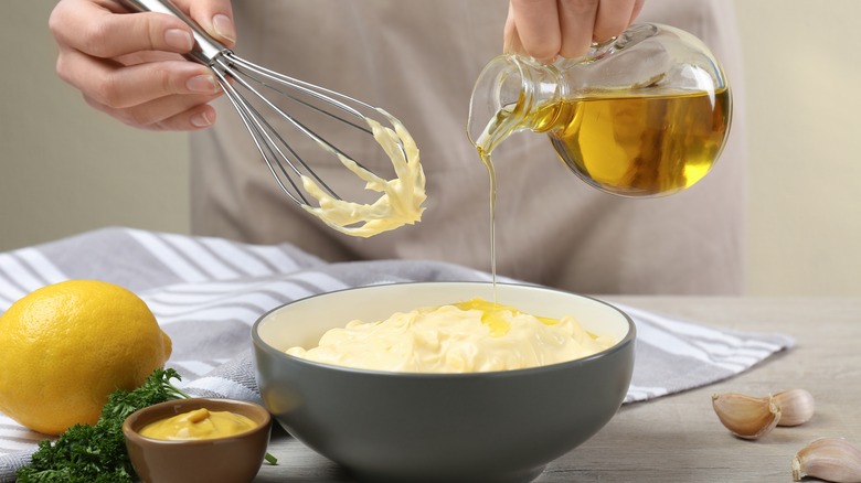 pouring oil into bowl of homemade mayonnaise