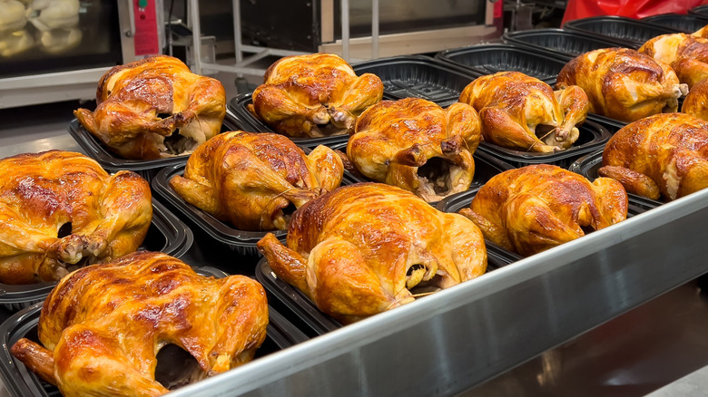 Rotisserie chickens in black plastic trays at the grocery store