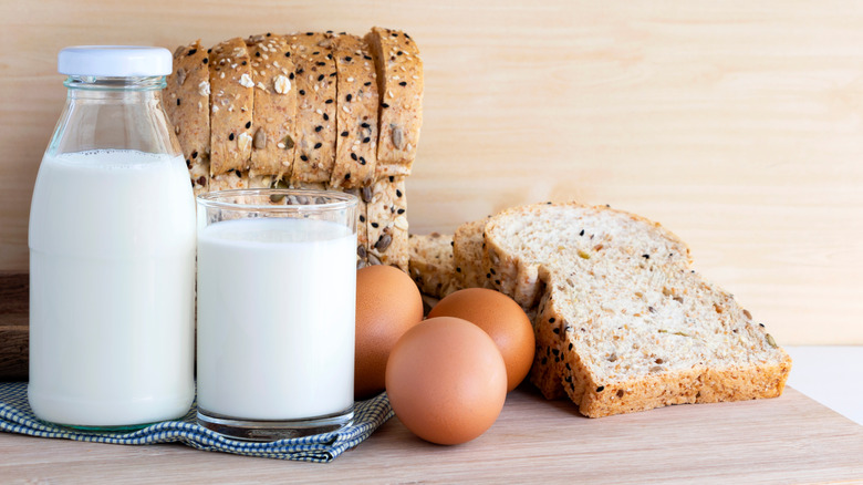 Milk, eggs, and bread on a wooden board