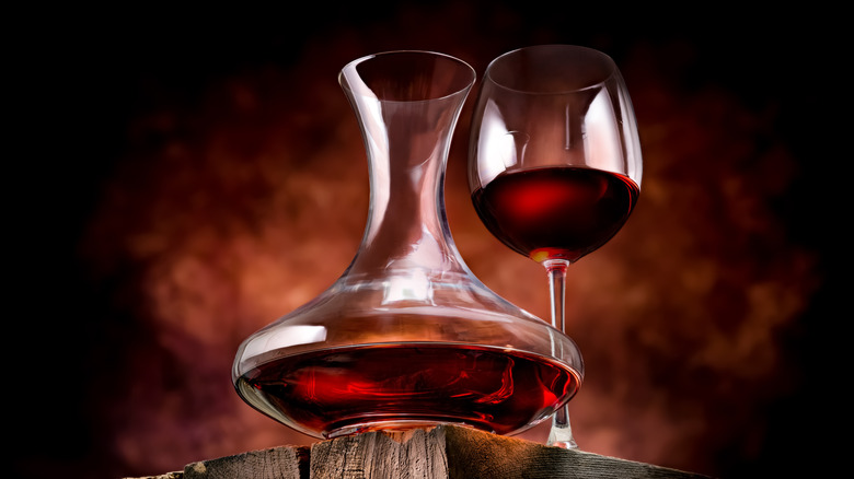 Red wine in wide decanter and wine glass, viewed from below.