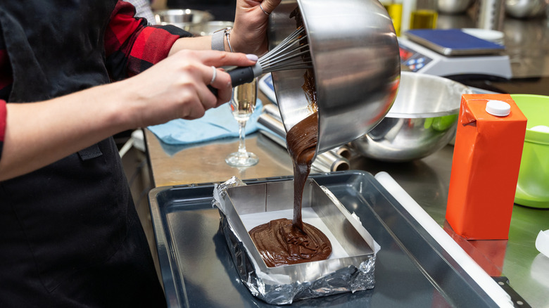 Person pouring chocolate batter into pan.