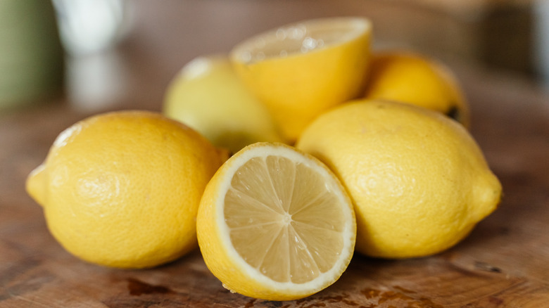 Whole and cut lemons are arranged on a wooden surface