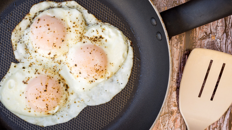 Over easy eggs in a pan with a spatula
